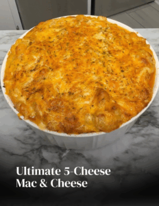 Ultimate 5-cheese mac and cheese in a white baking dish with a bubbly golden cheese crust on a marble countertop.